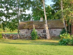 an old barn with a rock wall in front of it at Päikesemajake 2 in Soonlepa
