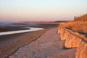 une plage de sable avec une clôture et l'océan dans l'établissement Cottage de la mer, au Crotoy
