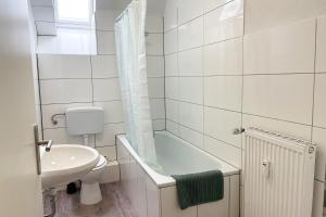 een badkamer met een bad, een wastafel en een toilet bij cozy 2-room Apartment in Brühl