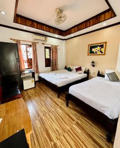 2 letti in una camera con pavimenti in legno di Singharat Boutique House a Luang Prabang