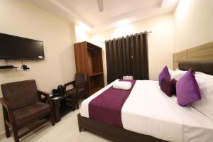 Habitación de hotel con cama y silla en Perfect Stayz Dwarkesh - Hotel Near Haridwar Railway station, en Haridwar