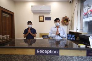 Dois homens com máscaras de rosto a rezar no balcão. em Perfect Stayz Dwarkesh - Hotel Near Haridwar Railway station em Haridwar