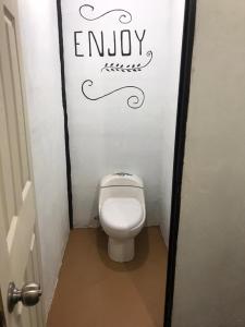 a bathroom with a toilet with the word enjoy on the wall at Poas Volcano Rooms in Fraijanes