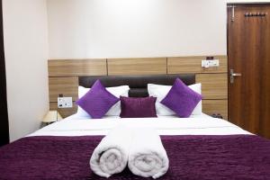 Perfect Stayz Dwarkesh - Hotel Near Haridwar Railway station في حاريدوار: غرفة نوم بسرير كبير مع مخدات ارجوانية وبيضاء