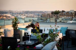 dwie kobiety siedzące na balkonie z widokiem na miasto w obiekcie Palazzo Ignazio w mieście Valletta