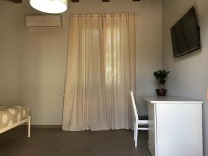 a room with a curtain and a desk and a television at Azienda agricola Crilù in Milazzo
