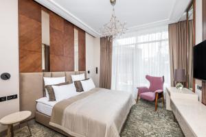 a bedroom with a large bed and a pink chair at Zolotoy Ruchey in Sestroretsk