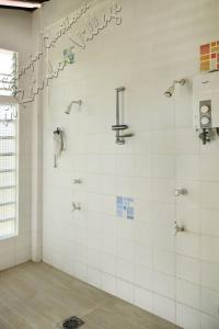a bathroom with a shower with white tiles at Guanyin Guesthouse at Rainbow Village in Maricaban