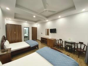 a room with two beds and a desk and a television at Tien Minh Hotel 113 Le Thanh Nghi in Hanoi