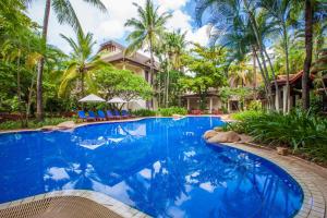 a swimming pool in front of a house with palm trees at Settha Palace Hotel in Vientiane
