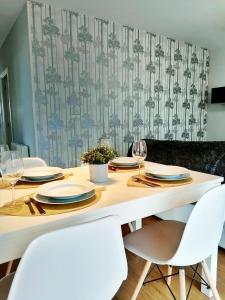 einem Esstisch mit weißen Stühlen und einem Tisch mit Gläsern in der Unterkunft Vivienda de uso turístico Piso de Castro in Sardiñeiro