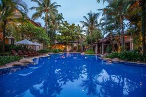 a large swimming pool with palm trees in a resort at Settha Palace Hotel in Vientiane
