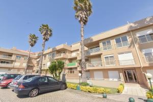 a parking lot in front of a building with palm trees at Rocha’s Apartment REMODELADO! Na praia com terraço in Vila Nova de Gaia