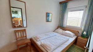1 cama en un dormitorio con espejo y silla en ROBERTO Haus KMB Seeappartement direkt am Ossiacher See mit Hallenbad, en Tschöran