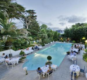 a pool with tables and chairs and people sitting around it at Hôtel Parc Victoria in Saint-Jean-de-Luz