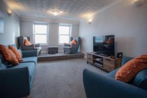 a living room with couches and a flat screen tv at North Beach Heights - 2 Bedroom Penthouse - Tenby in Tenby