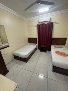 Habitación con 2 camas y cortina roja. en Makkah Hotel en Qinā