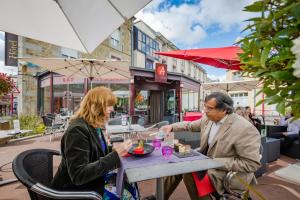 Ein Mann und eine Frau sitzen an einem Tisch in einem Restaurant in der Unterkunft Logis Hôtel Restaurant Le Fruitier in Villedieu-les-Poëles