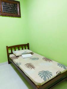 a bed in a room with a green wall at Izzara Iskandar Puteri Homestay Gelang Patah in Gelang Patah