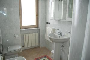 a white bathroom with a sink and a toilet at CASA FRUSCIONE in Magliano Alfieri