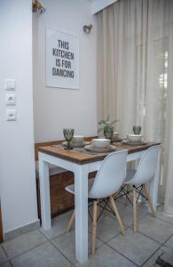 塞薩羅尼基的住宿－Fobillo Apartment at Charilaou，餐桌、白色椅子和墙上的照片