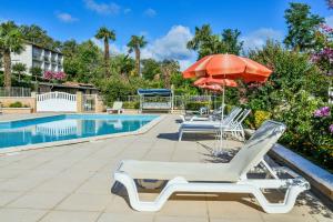 a swimming pool with lounge chairs and an umbrella at Aux Tauzins in Montfort-en-Chalosse