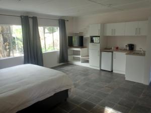 1 dormitorio con 1 cama y cocina con armarios blancos en Garden Court B&B, en Queenstown
