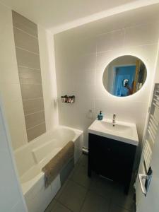 La salle de bains est pourvue d'une baignoire, d'un lavabo et d'un miroir. dans l'établissement Superbe appartement à 10min du centre de Lyon, à Villeurbanne