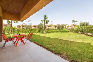 un patio con mesa, sillas y césped en Appartement Pied dans l'Eau - jardin privée en Marrakech