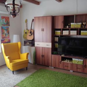 salon z żółtym krzesłem i telewizorem w obiekcie Parányi Porta Bakonybél w mieście Bakonybél