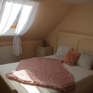 a bedroom with a bed with a pink blanket and a window at Parányi Porta Bakonybél in Bakonybél