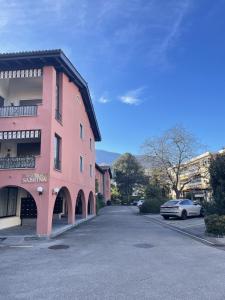 un bâtiment rose avec une voiture garée à côté dans l'établissement Mon Bijoux, à Ascona