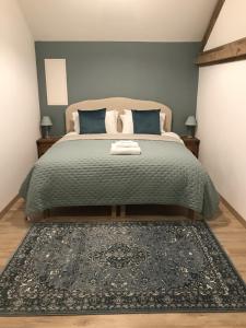 een slaapkamer met een bed met een groene sprei en een tapijt bij Logis de L'Arceau in Celles