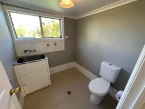 a bathroom with a toilet and a sink and a window at Charming 3 bedroom Workers Accommodation in Grafton +5 photos