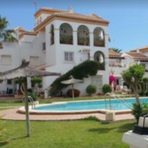 un gran edificio con una piscina frente a él en Casa Millie en Playa Flamenca
