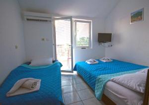 a bedroom with two beds with blue sheets and a window at Villa San Marco in Budva