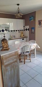 een keuken met een tafel en stoelen in een kamer bij En plein cœur de l’Île d'Oléron, suite parentale. in Dolus d'Oléron