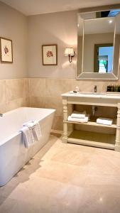 bagno con vasca, lavandino e specchio di Marlfield House Hotel a Gorey