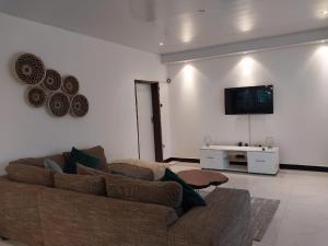 sala de estar con sofá y TV de pantalla plana en Kasuba Apartments, en Livingstone