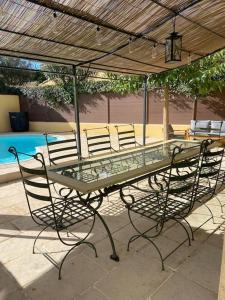 a glass table and chairs under an umbrella at Sublime Maison Proche Mer Avec Piscine in Sanary-sur-Mer