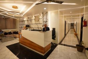 a man standing behind a counter in a lobby at The Royal Hotel in Haldwāni