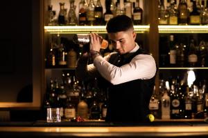 un hombre parado detrás de una barra con una botella de vino en The Atlantic Hotel - Small Luxury Hotels of the World, en St Brelade