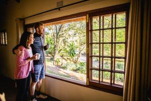 a man and a woman standing in front of a window at iNsingizi Lodge in Mid Illovo