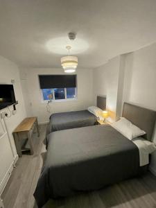 1 Schlafzimmer mit 2 Betten, einem Tisch und einem TV in der Unterkunft Top Twenty Bed and Breakfast in Windsor