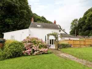 uma casa branca com um jardim e uma cerca em Spring Garden Cottage em Carmarthen