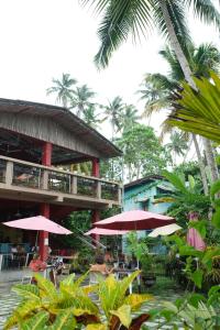 eine Gruppe von Menschen, die unter rosa Sonnenschirmen in einem Restaurant sitzen in der Unterkunft Mellow Hostel Sri Lanka in Ahangama