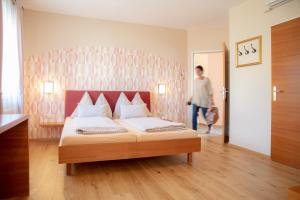 a bedroom with a bed and a man walking into a room at Restaurant Hotel Schrott in Kaibing