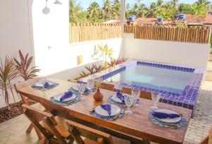 a dining table with chairs and a swimming pool at Casa Mar do Patacho in Pôrto de Pedras