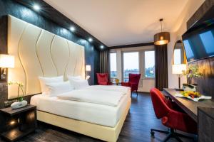 um quarto de hotel com uma cama, uma secretária e cadeiras em PLAZA Premium Schwerin Sure Hotel Collection by Best Western em Schwerin