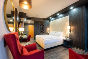 a hotel room with a bed and chairs and a mirror at PLAZA Premium Schwerin Sure Hotel Collection by Best Western in Schwerin